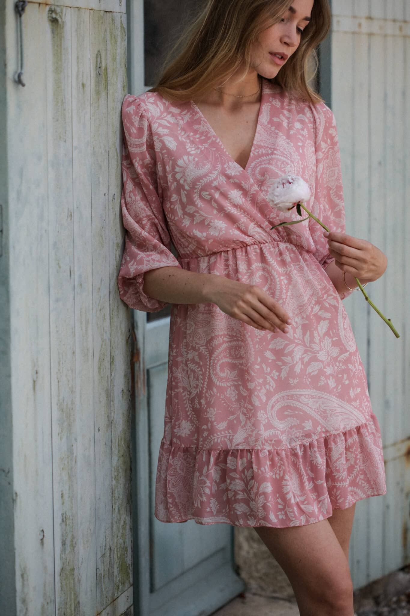 Pink two-tone cashmere print dress on mannequin with a flower in hand